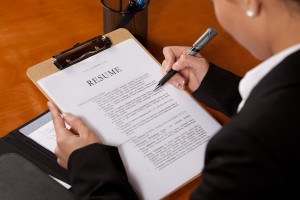 A Woman looking over a resume with a pen in her hand